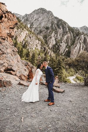 Wedding couple poses against dramatic mountain cliffs in a series of outdoor portraits.