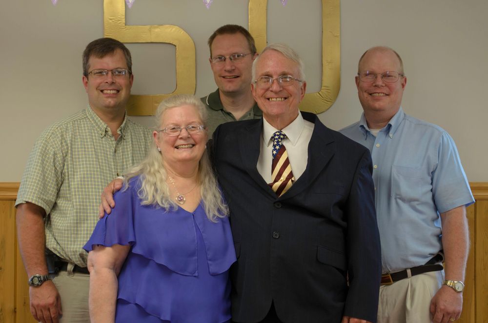 Group gathered for a photo in front of a golden wall at a formal event.