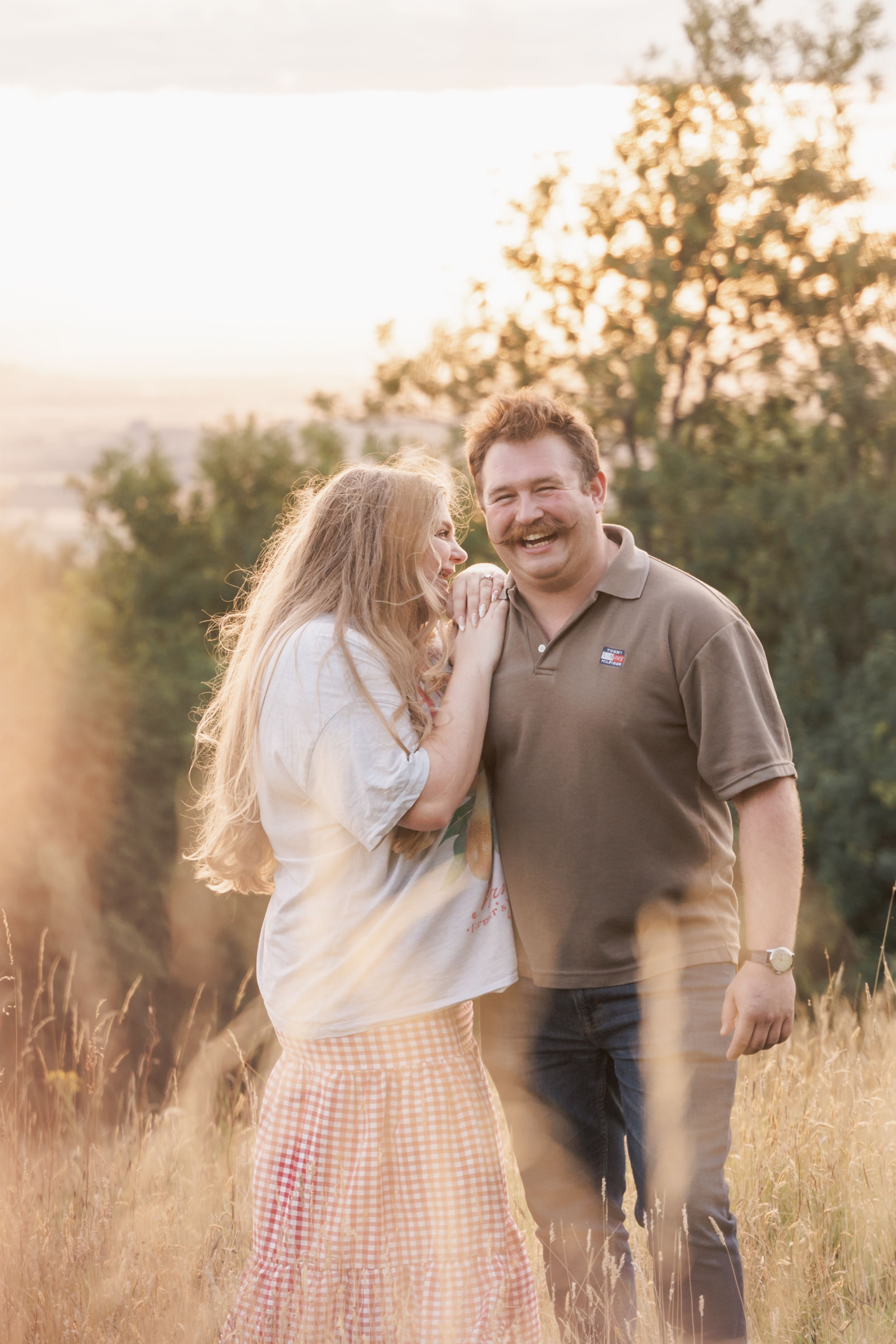 A couple laughs together during their sunset photoshoot in a natural outdoor setting.