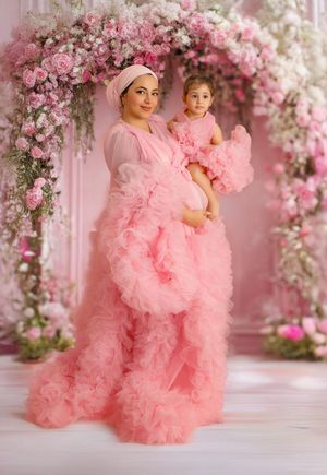 Dreamy pink floral photography scene with flowing tulle gowns and rose flower arch against soft pink backdrop.