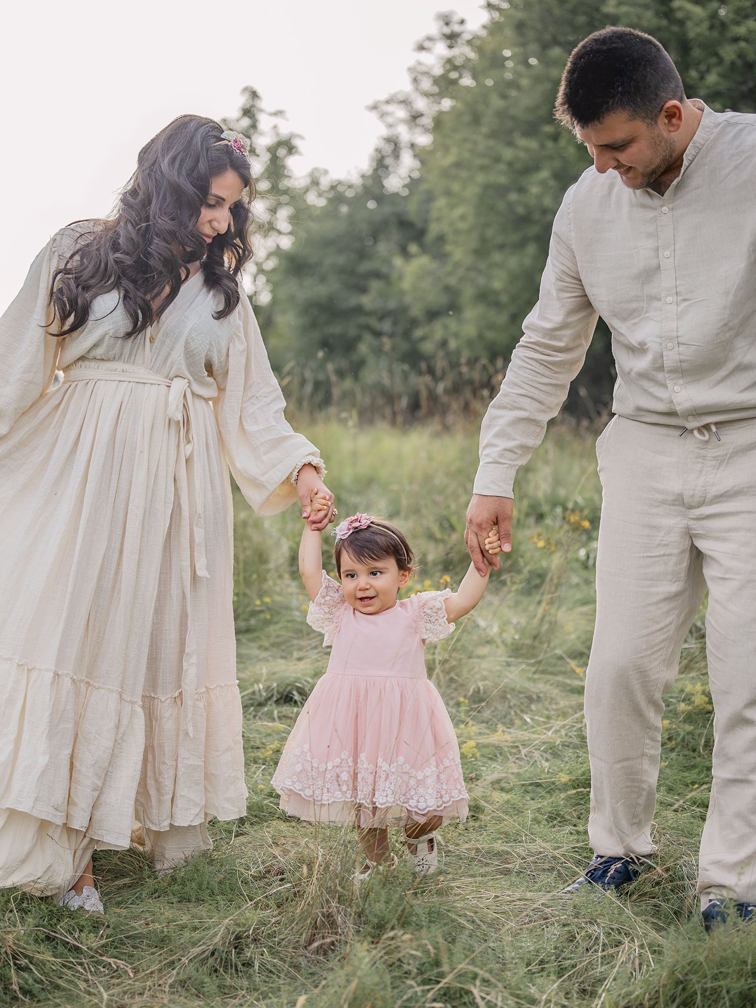 Familj går hand i hand i motljus på en äng, Familjefotografering i Västerås, MemoriesbyM.se