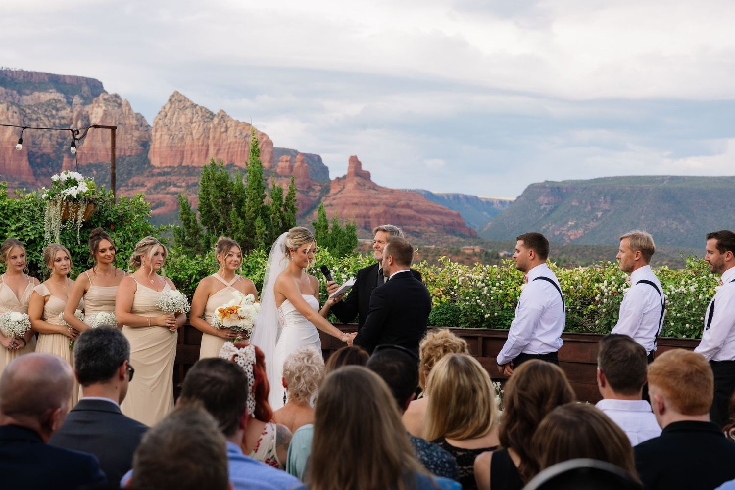 A wedding ceremony takes place outdoors with stunning red rock formations of Sedona Arizona in the background.