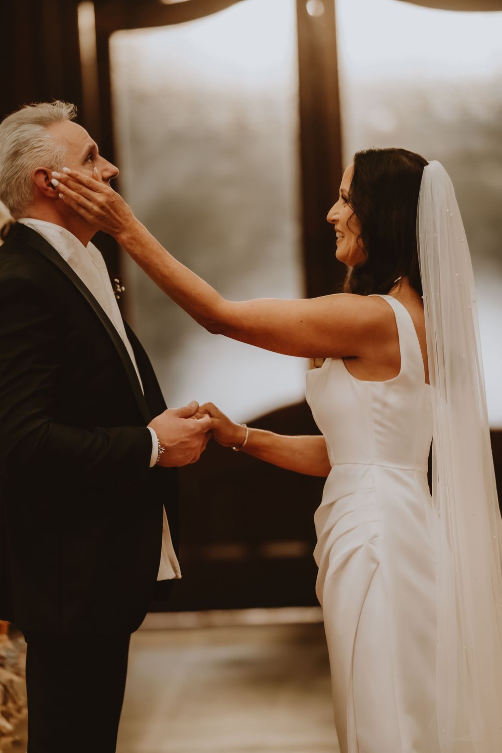 A joyful first look moment between newlyweds in a minimalist indoor setting captured in a candid style.