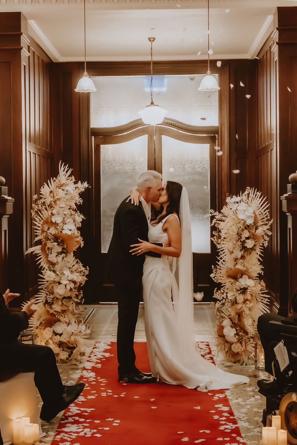 Couple sharing an intimate moment during their wedding ceremony amidst elegant floral arrangements and candlelight.
