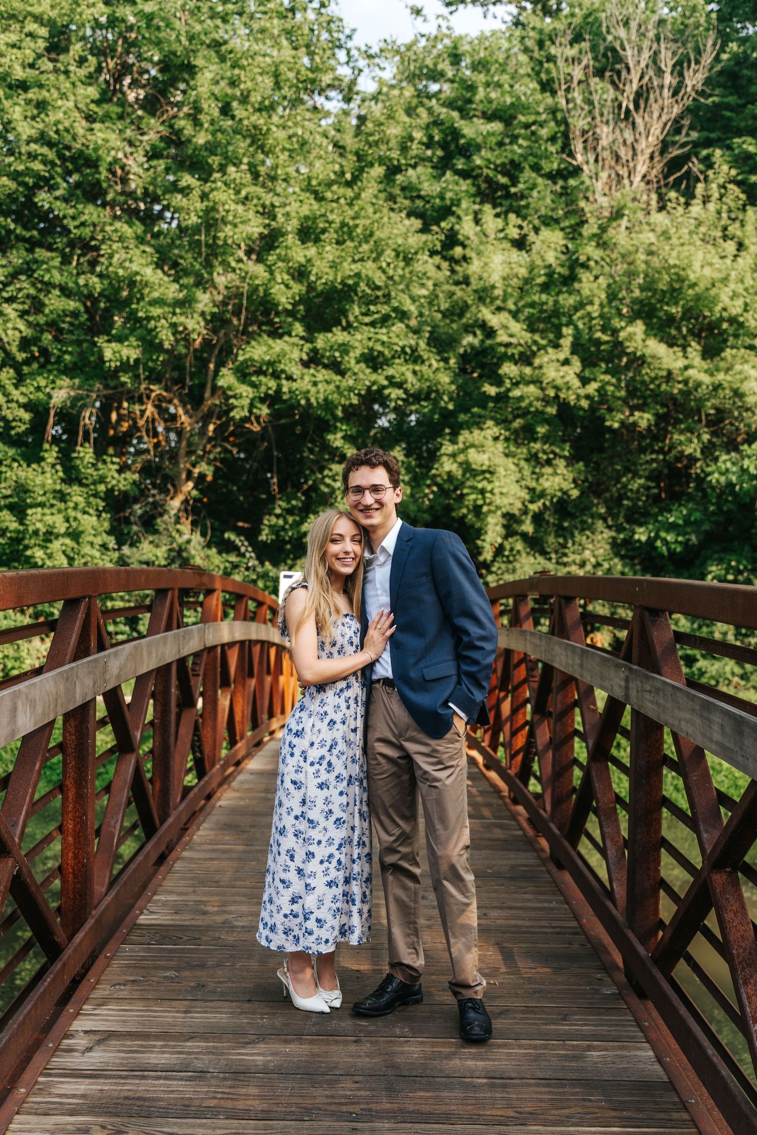 Couple sharing a romantic moment on a wooden footbridge surrounded by lush greenery.