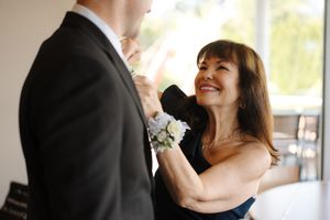 A couple in formal wedding attire laugh joyfully together during an intimate moment at their celebration.
