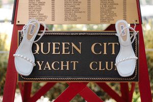 A vintage-style entrance sign for Queen City Yacht Club features gold lettering and nautical rope details.