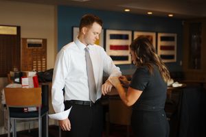 People in formal attire conversing in an office setting with framed artwork visible on the walls.