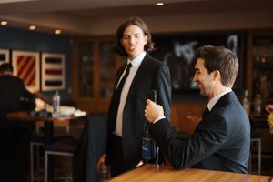 Business people gather in a dimly lit bar or restaurant for after work drinks and networking.