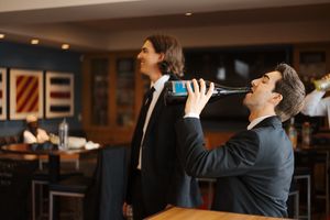 Two people in business attire share a drink together at an elegant bar.