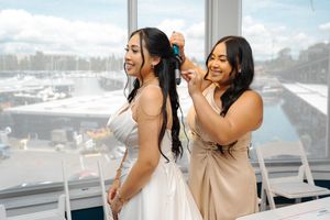Two friends laugh and enjoy each other's company while posing together by ocean view windows in a bright room.