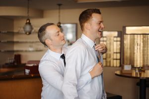 Inside a dimly lit room, people share an emotional moment while wearing white button-down shirts.