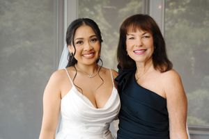 Two women wearing contrasting black and white dresses smile next to each other at an event.