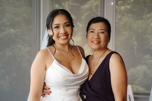 Two elegantly dressed women share a tender moment together in formal attire during a special occasion.