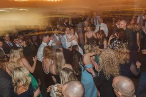 People dancing at a crowded party or reception under warm ambient lighting.
