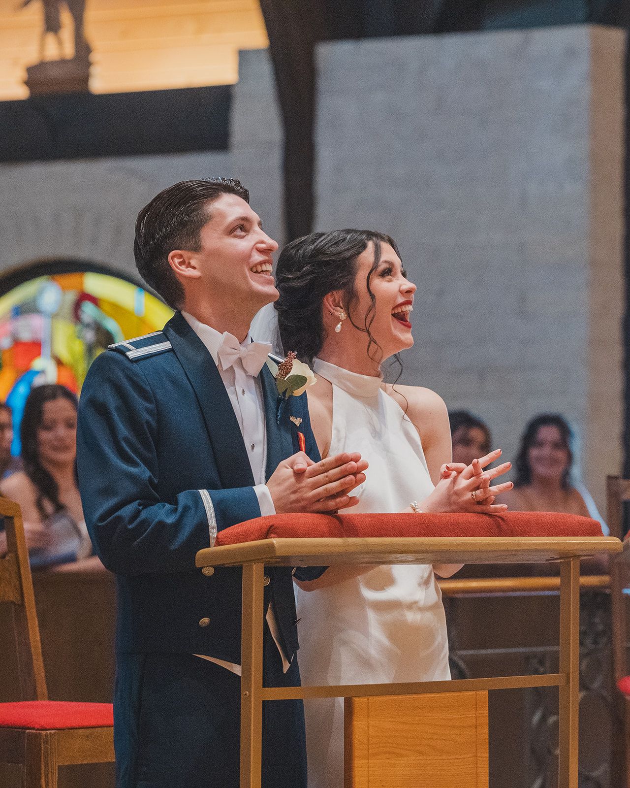 A bride and groom laugh joyfully while standing at the altar together during their church wedding ceremony.