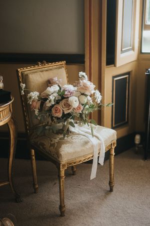 Vintage gold French chair adorned with soft pink and white roses and ribbons at Rise Hall.