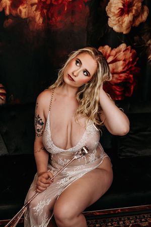 Artistic boudoir portrait in white lace lingerie against moody dark backdrop with red tones. Nice & Naughty Store Event Grand Rapids MI