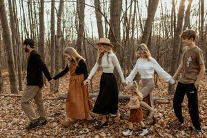 Outdoor autumn photoshoot in a wooded area with warm earth tones and natural light.
