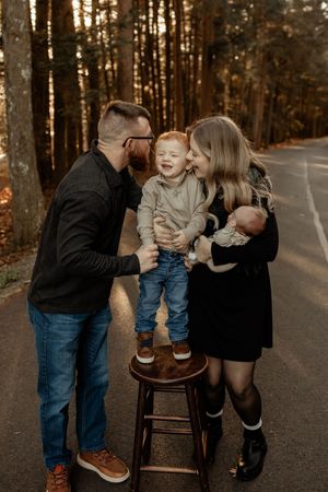 A family shares a tender moment together on a wooded path during golden hour.