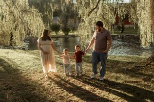 A golden sunset illuminates a path where people walk together in a wooded park on a warm afternoon.