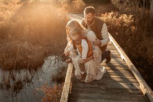 Candid family moments captured at sunset on a wooden boardwalk in warm autumn tones.