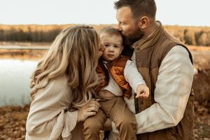 A romantic couple embraces in a golden field during sunset creating an intimate autumn portrait.