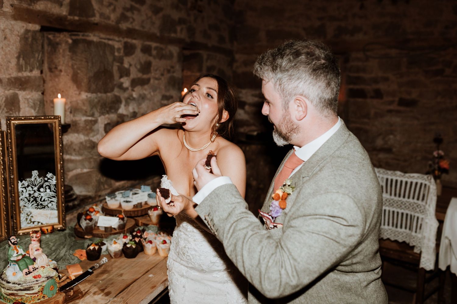Couple eating cake and celebrations at rustic brick venue with dim lighting.