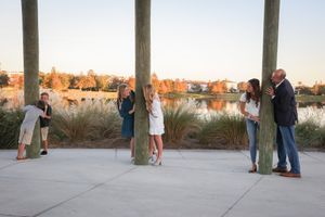 A group stands along a wooden boardwalk with water and trees visible in the background.