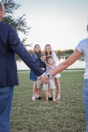 Candid shots of family members playing and posing on grass near water.