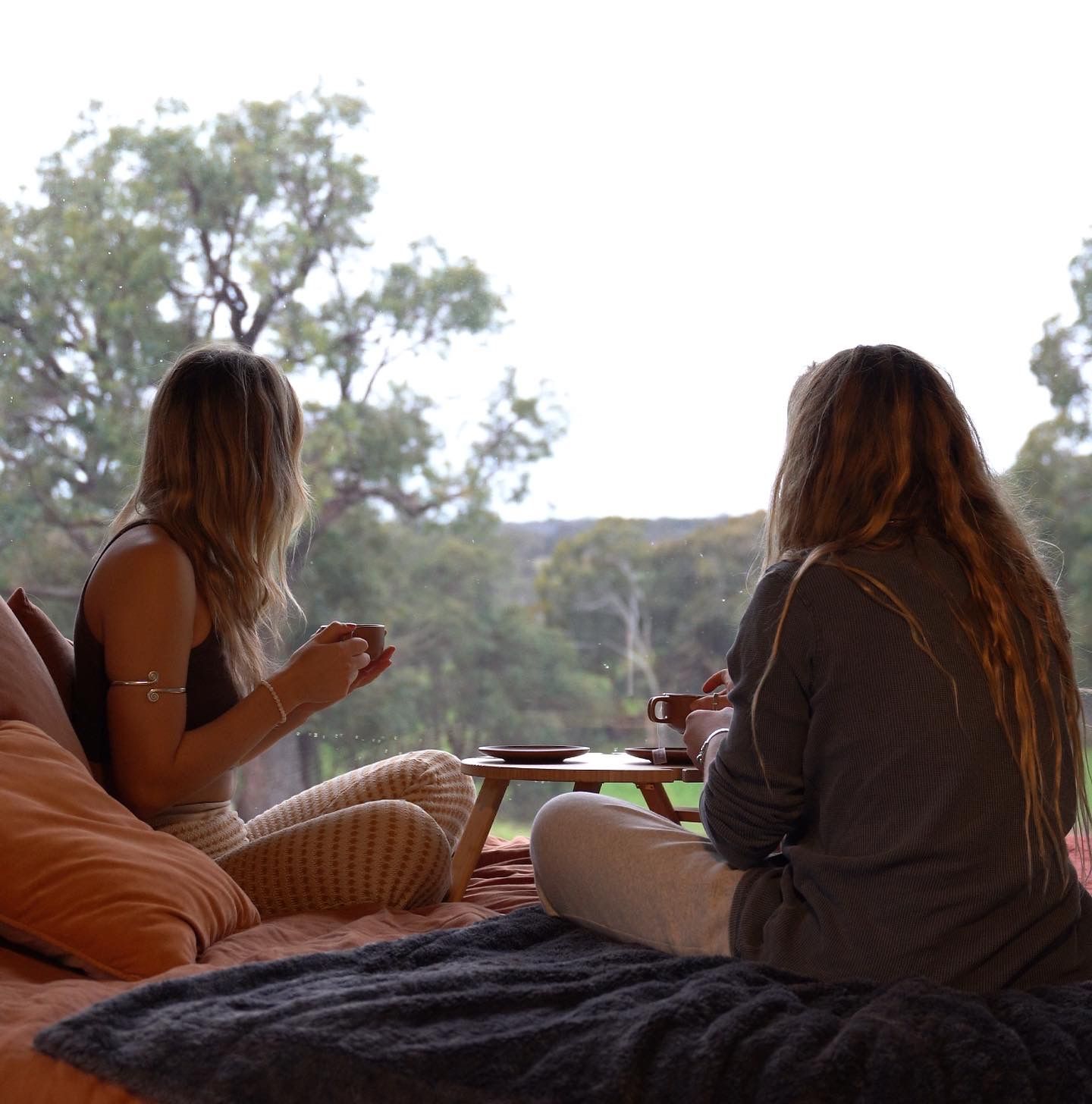 Two people enjoying breakfast in bed while overlooking scenic countryside views.