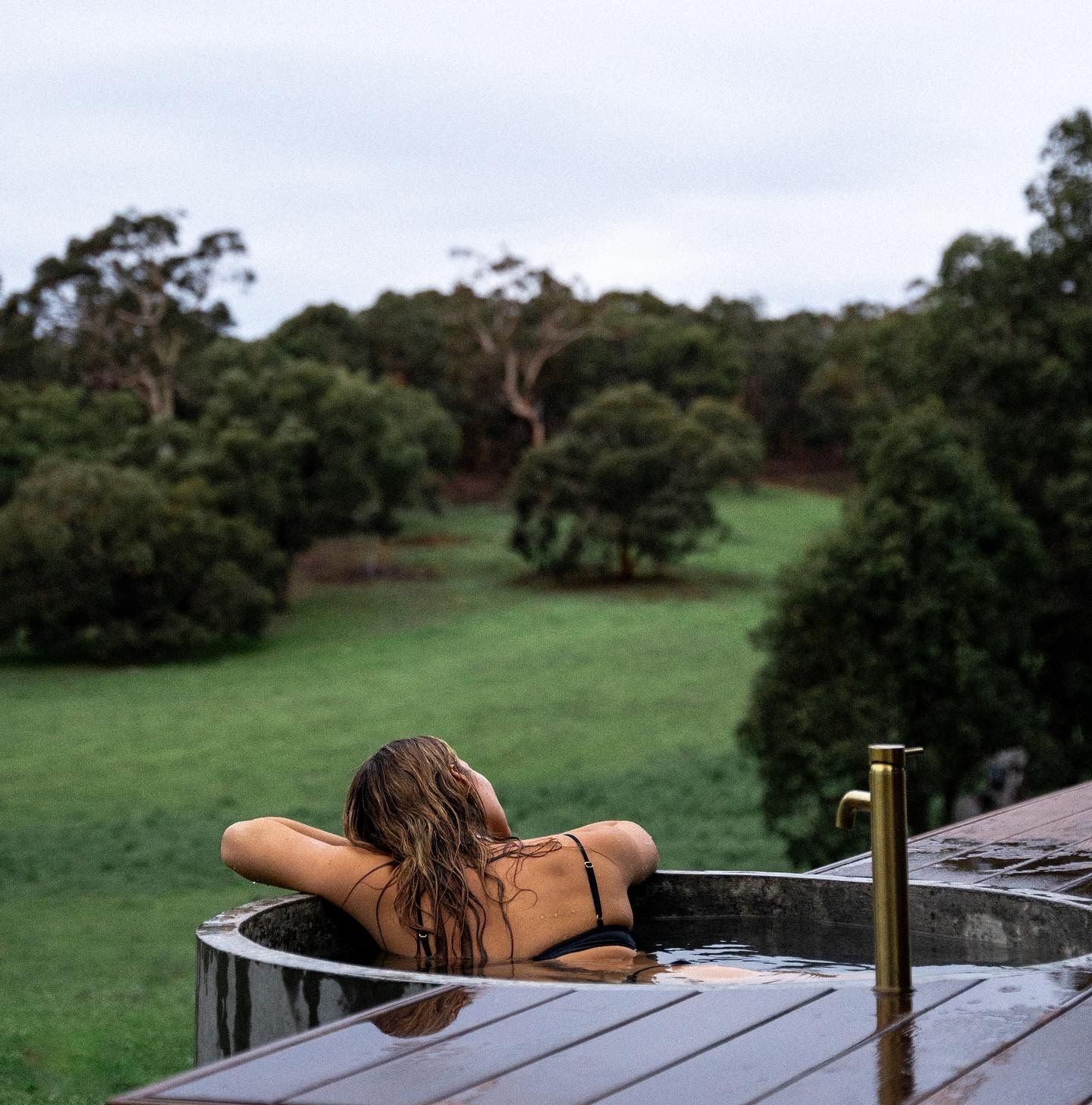 Relaxing outdoor view of Australian countryside from a deck with rustic wooden furniture.