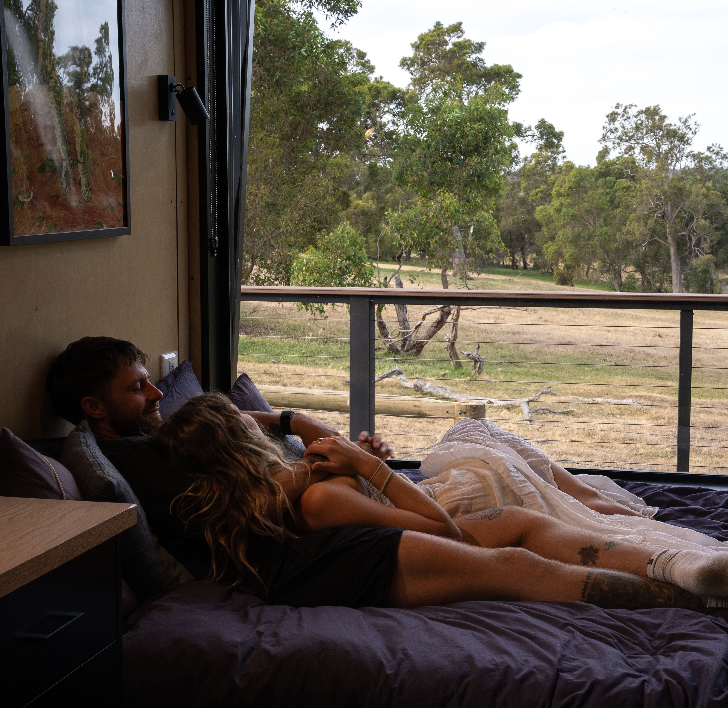 Relaxing in a cozy camper bed with scenic bushland views through the window.