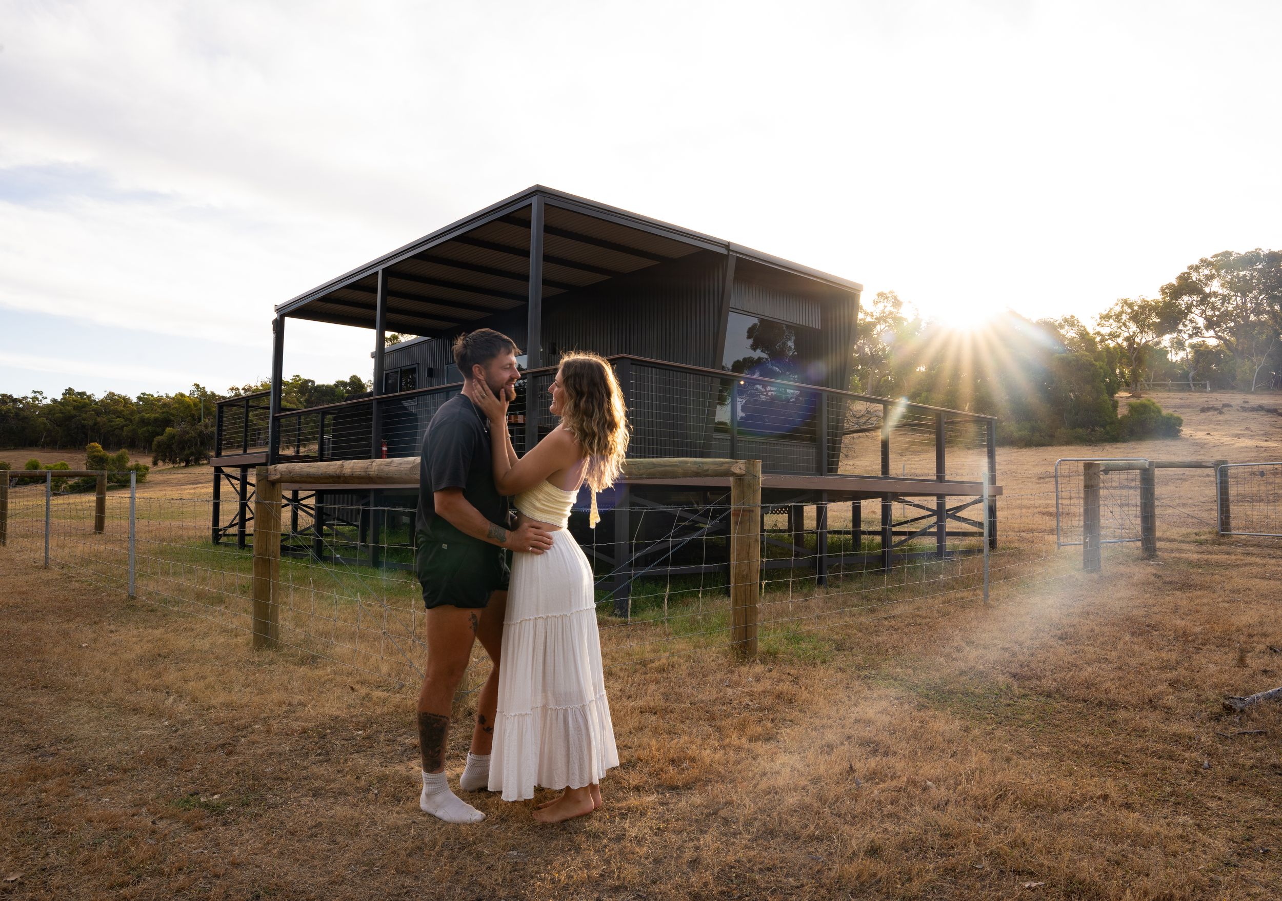 Romantic moment outside an elevated cabin at sunset in rural Australia.