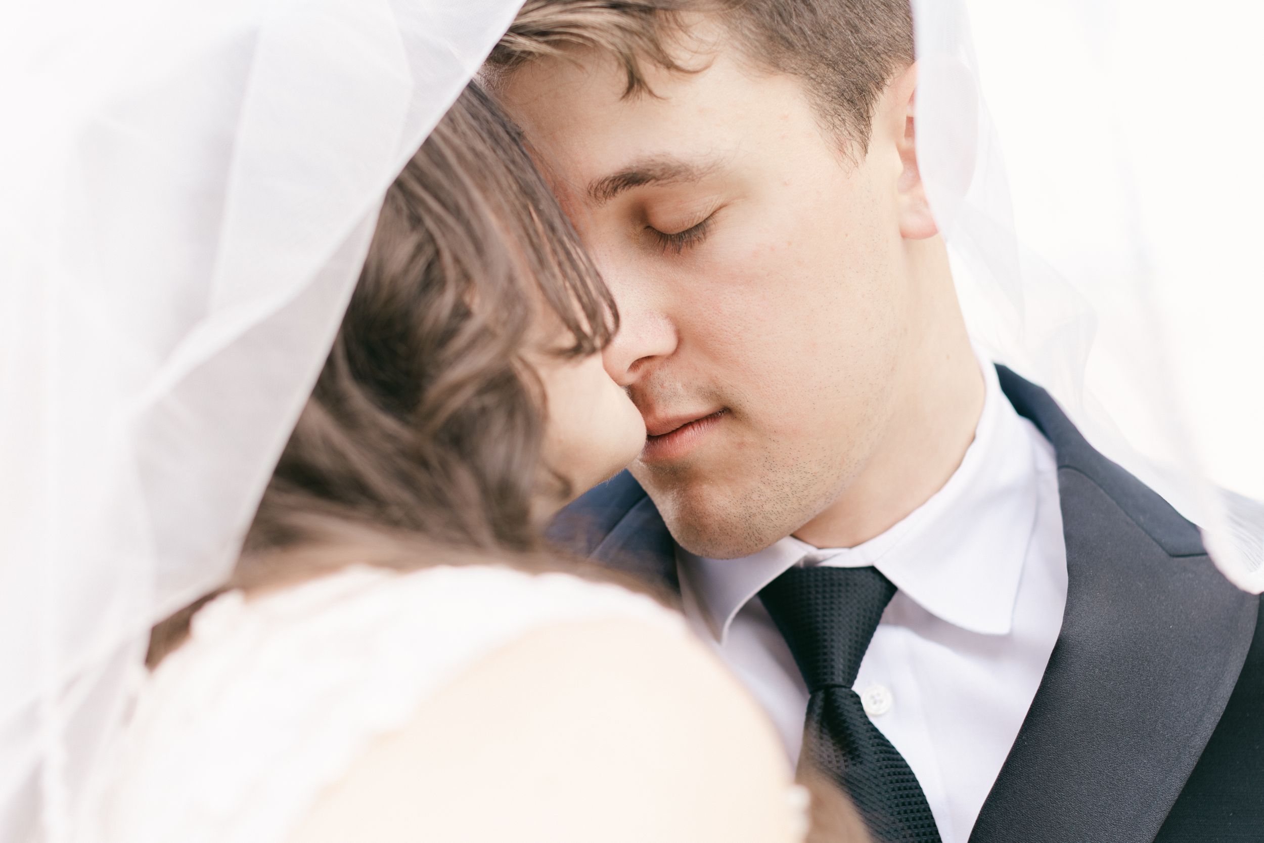 Close-up romantic moment between newlyweds in formal wedding attire.