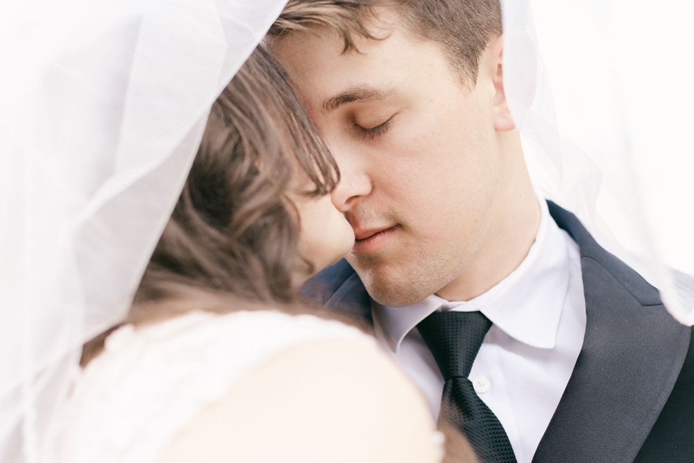 Close-up romantic moment between newlyweds in formal wedding attire.