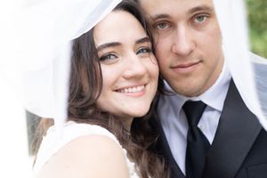Intimate portrait of newlyweds sharing a tender moment against white background.
