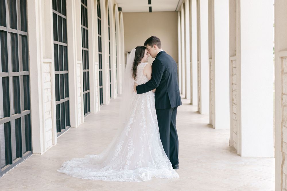 Elegant wedding couple photographed in a classic columned corridor.