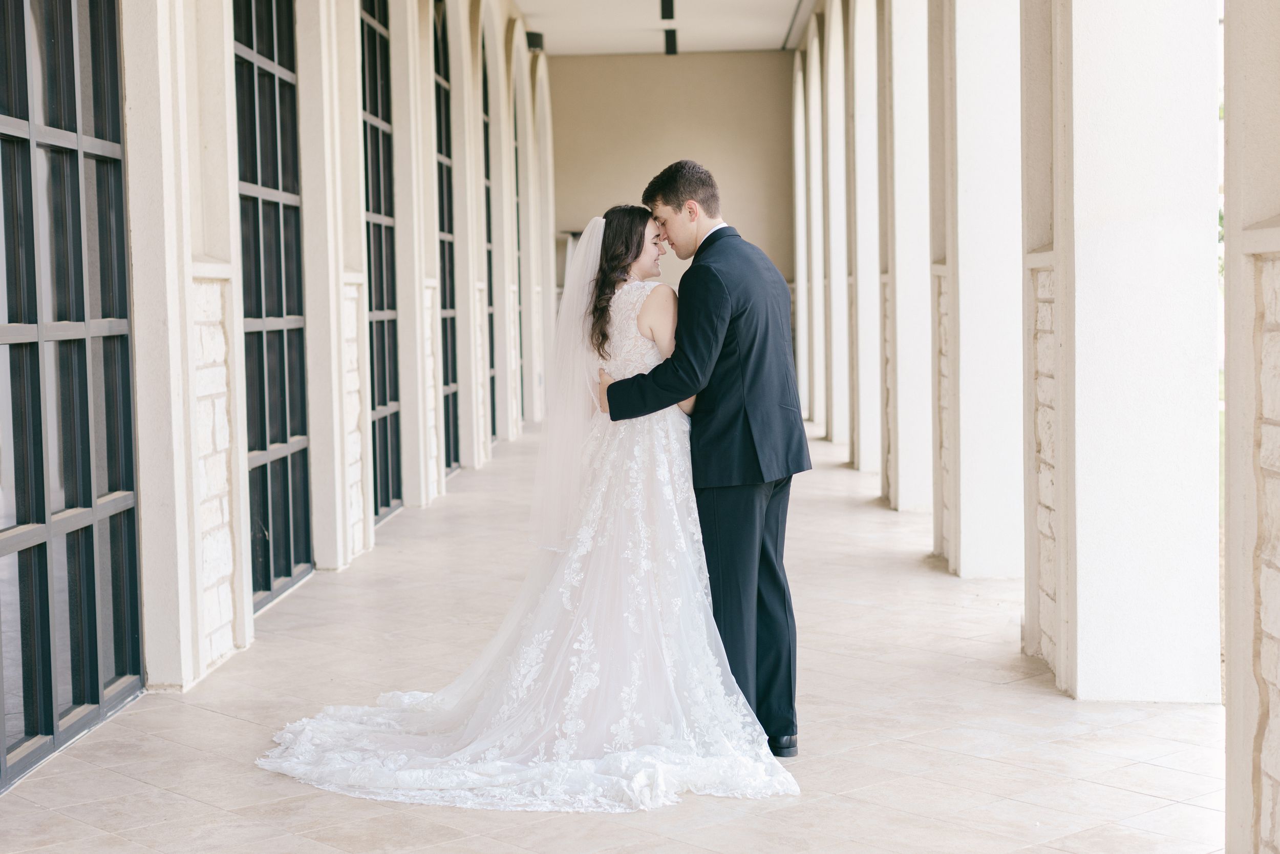 Elegant wedding couple photographed in a classic columned corridor.