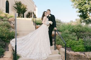 Wedding couple photographed in front of a chapel with beautiful landscaping and garden paths.