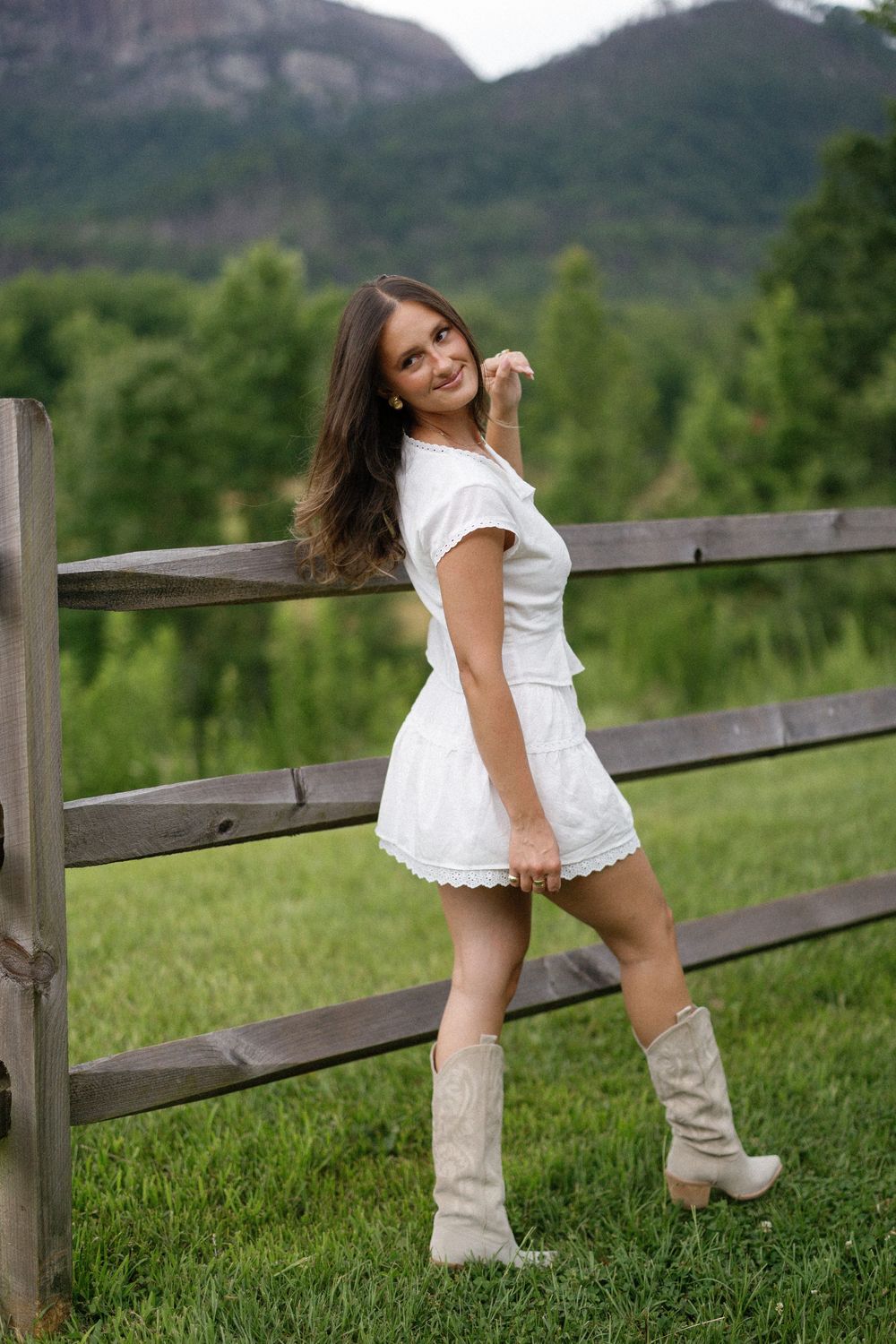A series of dynamic poses against a rustic wooden fence with rolling green hills and forest in the background.