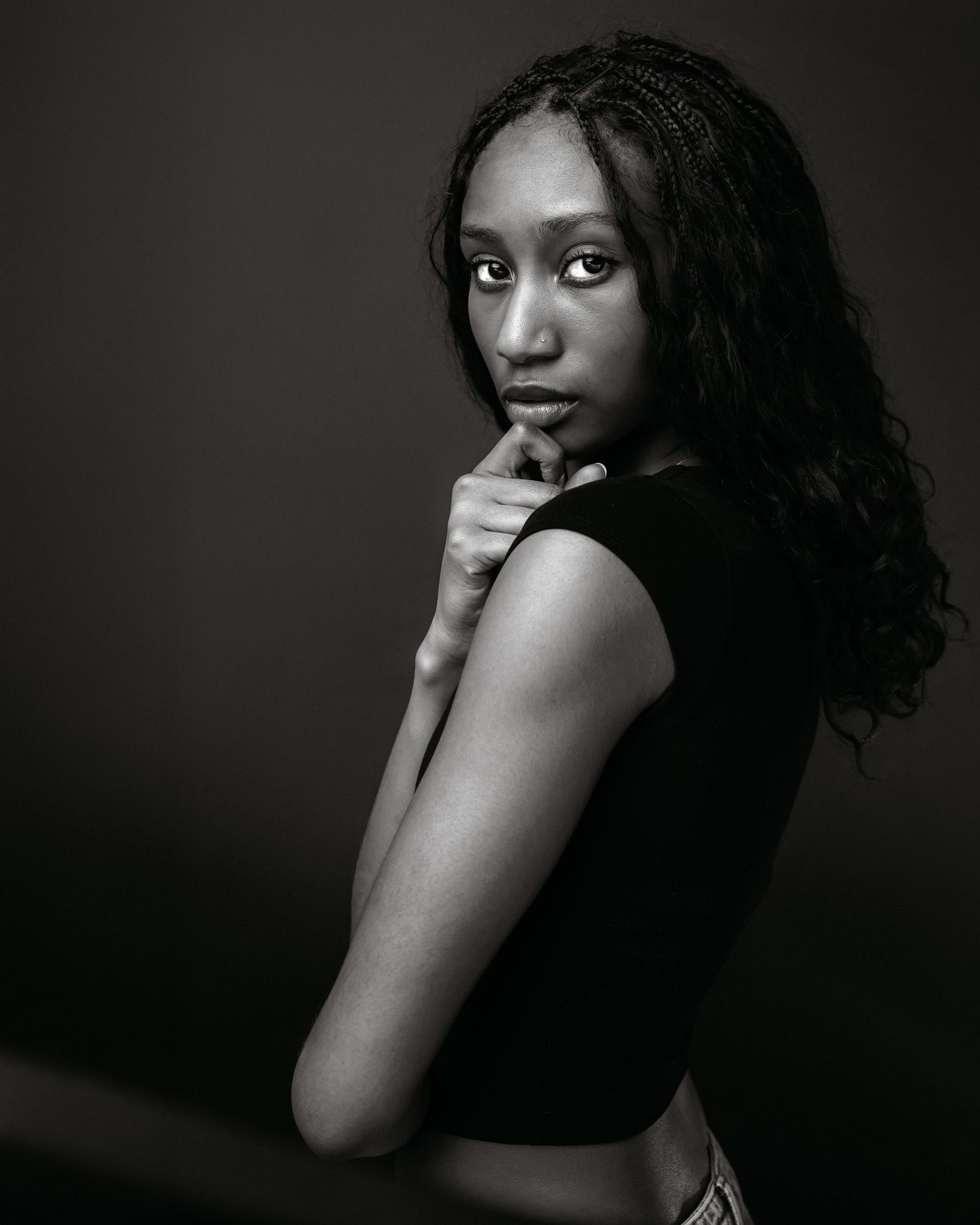 Dramatic black and white portrait showcasing natural curly hair and elegant pose.