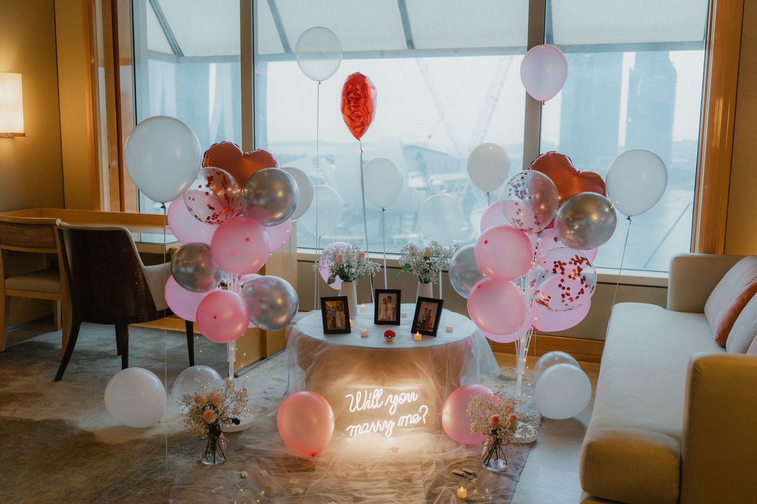 Romantic restaurant setting with pink and white balloons and fairy lights creating an intimate ambiance.