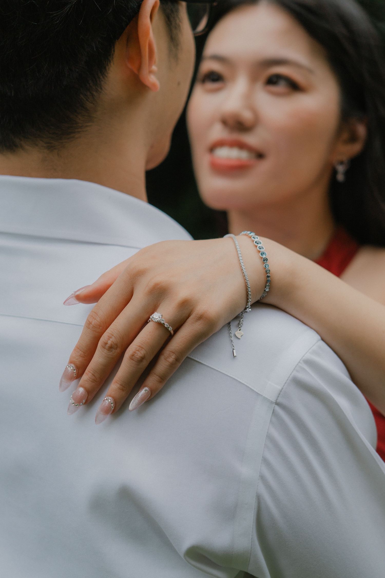 A close-up view shows a person's hand gently resting on someone's shoulder wearing a light gray dress shirt.