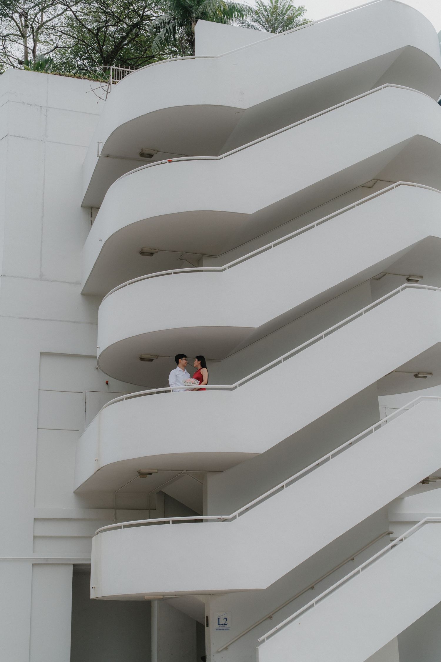 Modern white building exterior featuring curved architectural balconies against a cloudy sky.