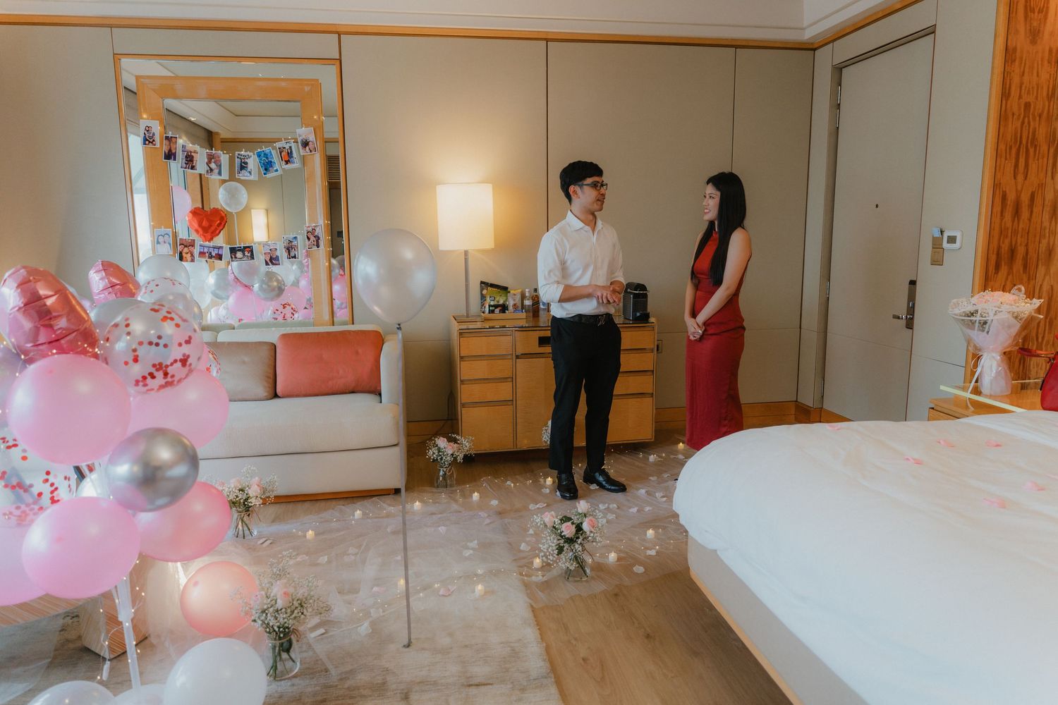 Romantic hotel room setup with pink balloons and festive decorations.