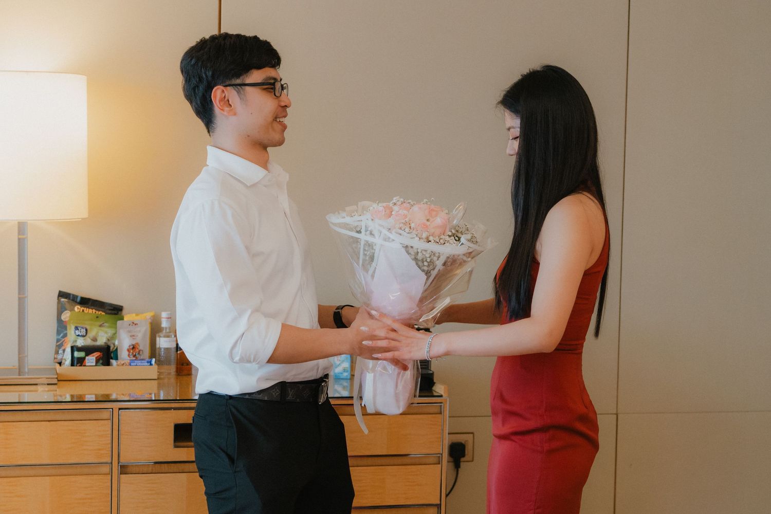 Two people conversing at a reception desk in an elegant indoor setting.