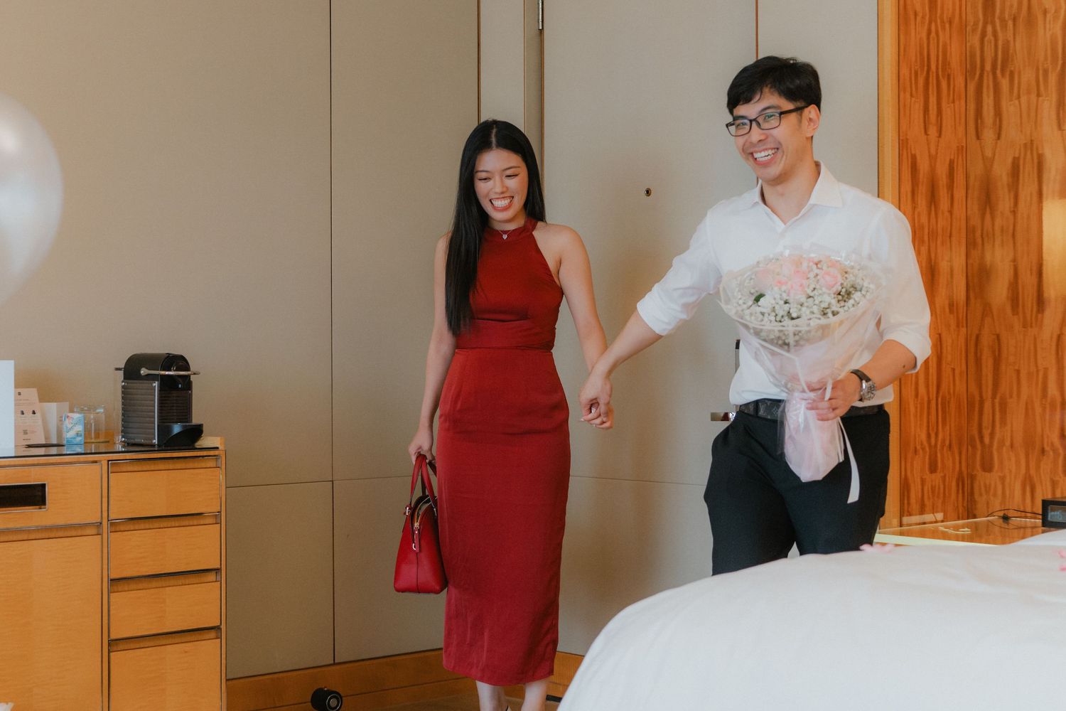 A couple celebrating their engagement in a room decorated with pink and white balloons.