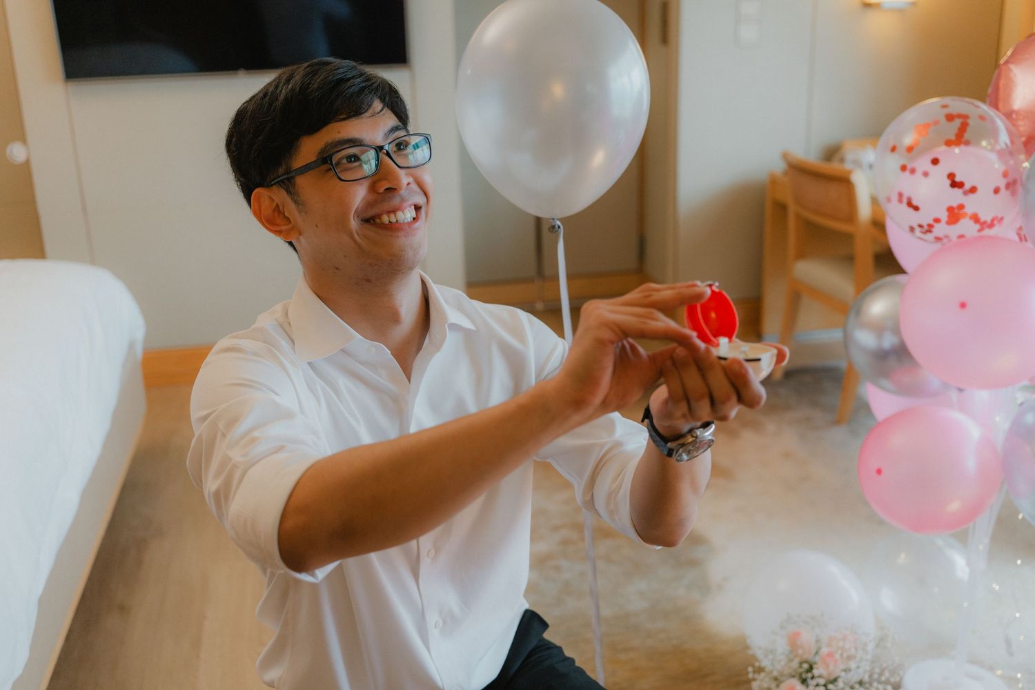 Indoor celebration setting with white and pink balloons and romantic lighting.