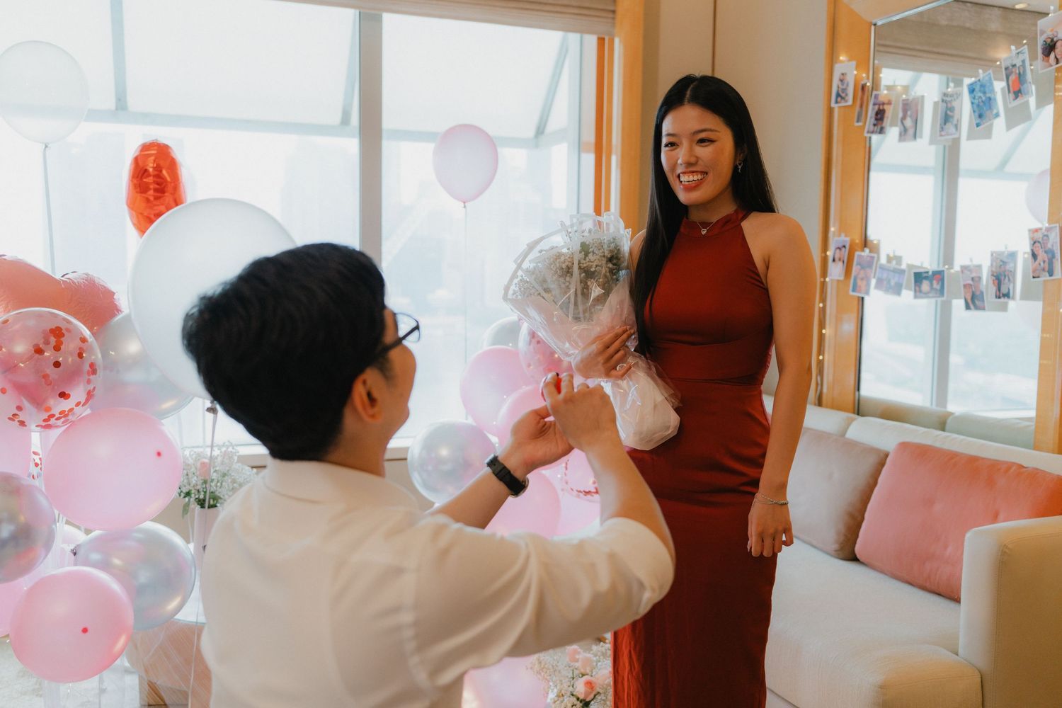 Engagement celebration moment captured as couple interacts playfully with festive balloons.